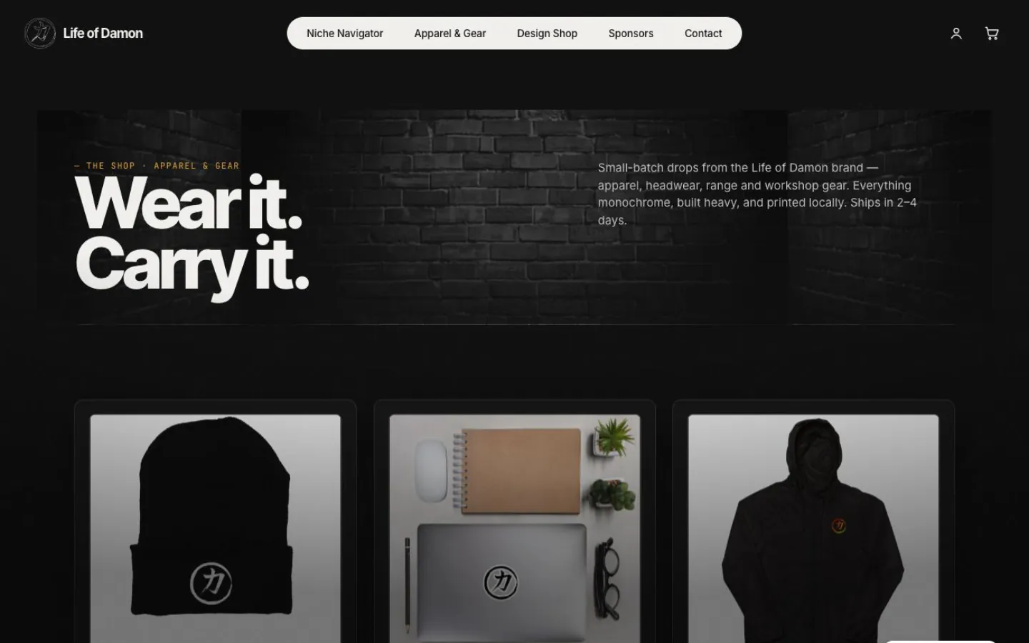 The Life of Damon apparel shop: a full-width brick photo with the headline “Wear it. Carry it.” above a row of three monochrome product cards.